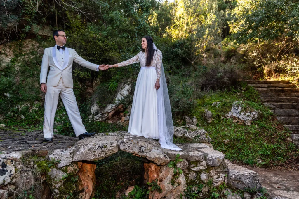 Bride and groom holding hands on a stone bridge during their wedding in Chania, Crete
