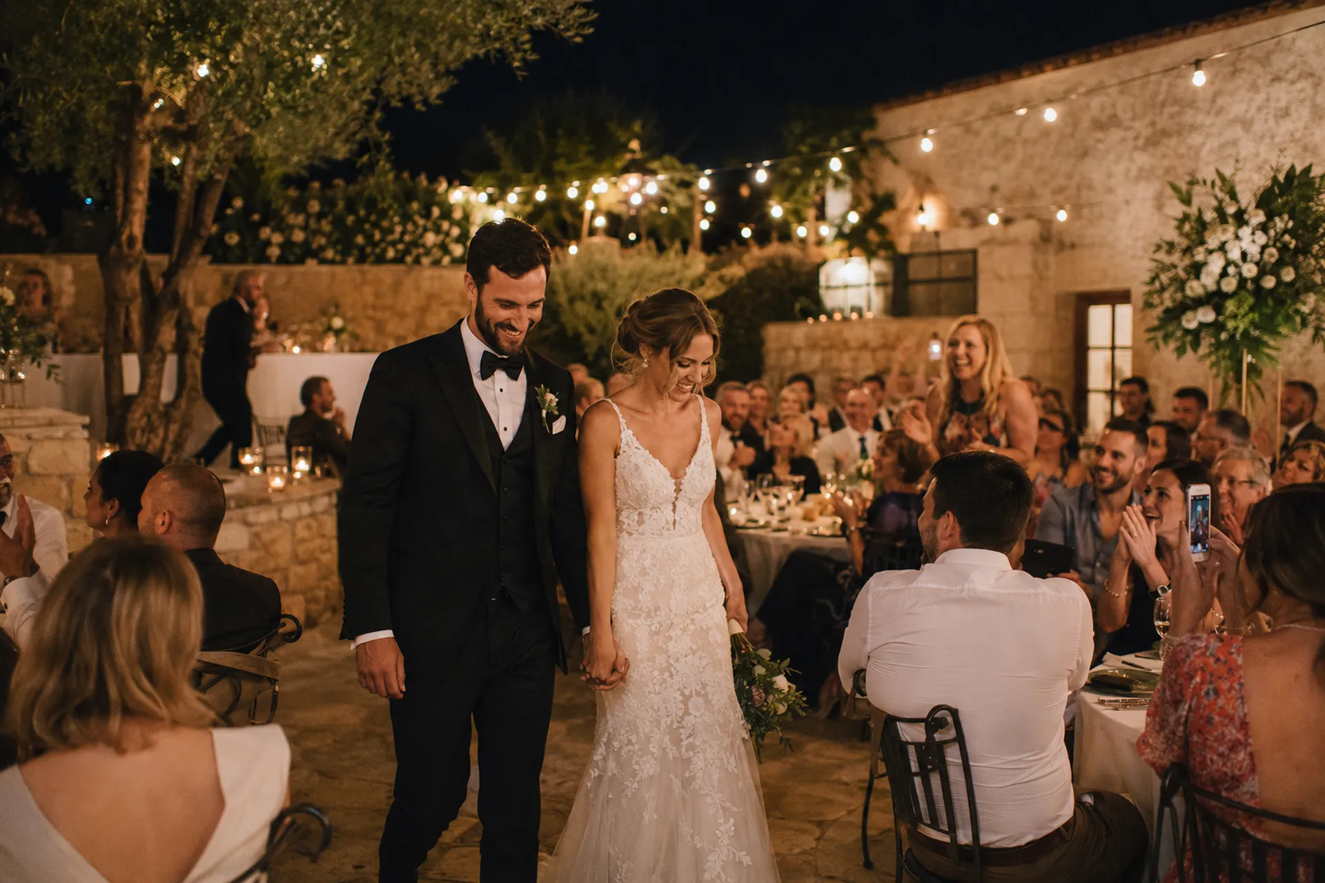 Bride and groom walking through their evening wedding reception in Crete